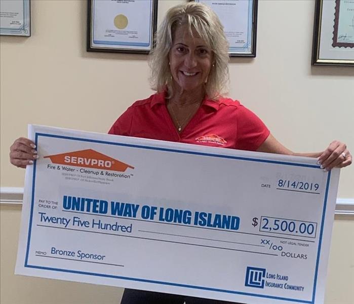 female employee holding a $2500 check donation